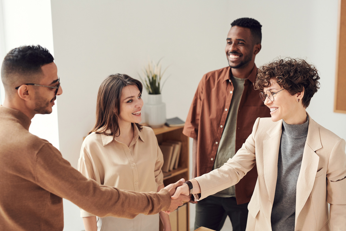 Two professionals shaking hands with other colleagues in a group